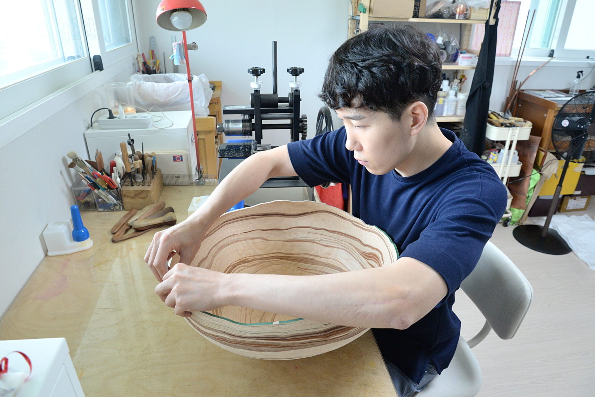 Junsu Kim dans son atelier, posant les lanières de cuir